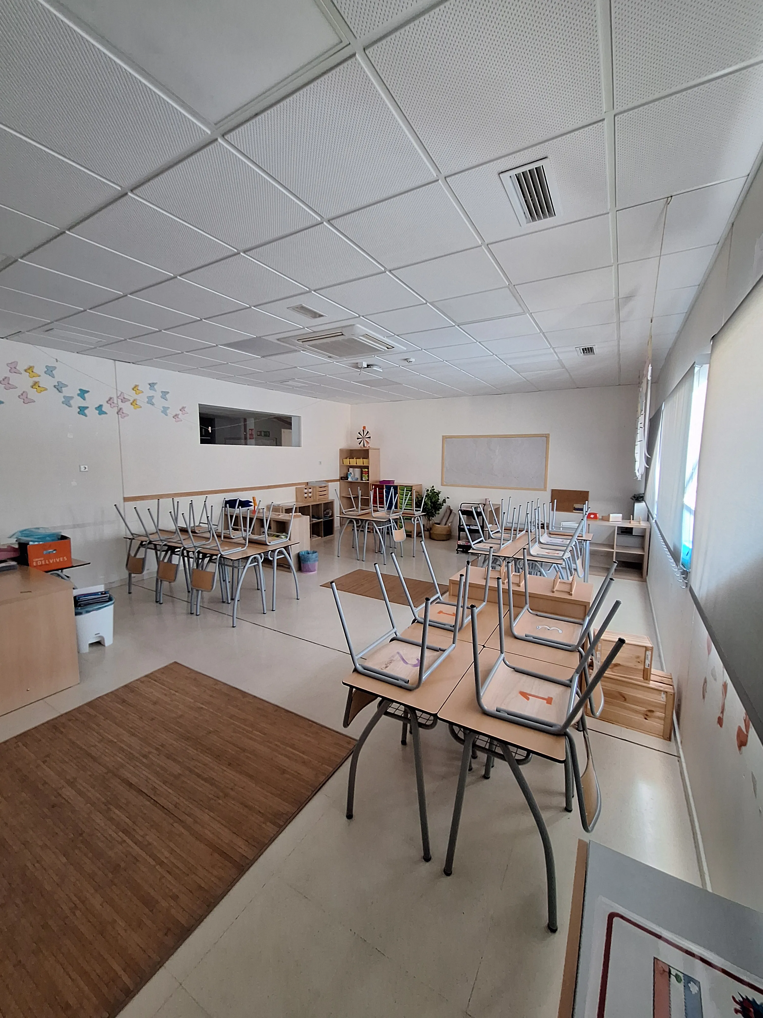 Aula preparada con mesas, sillas y materiales